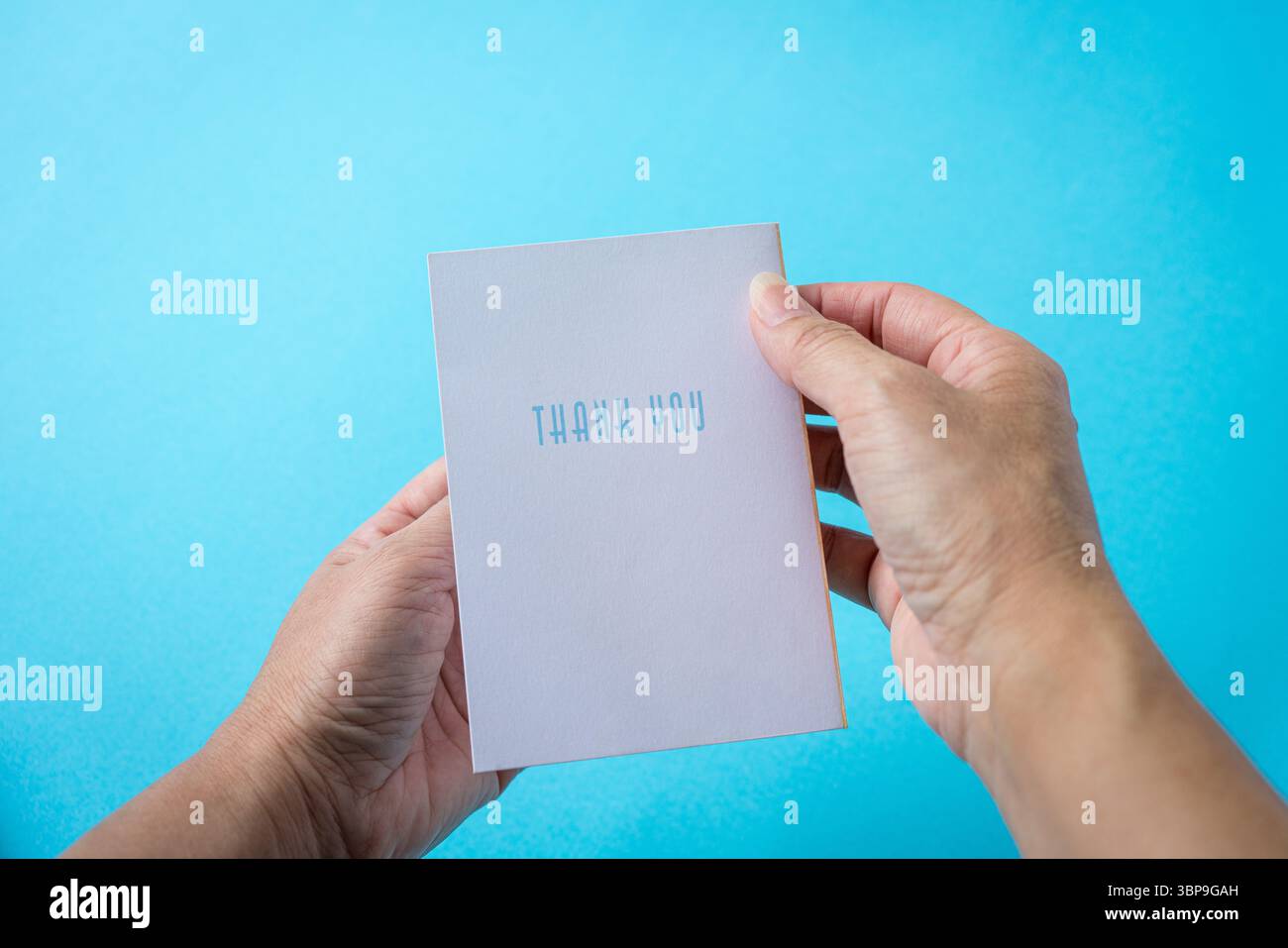 Con un biglietto di ringraziamento. Sullo sfondo azzurro. Foto Stock