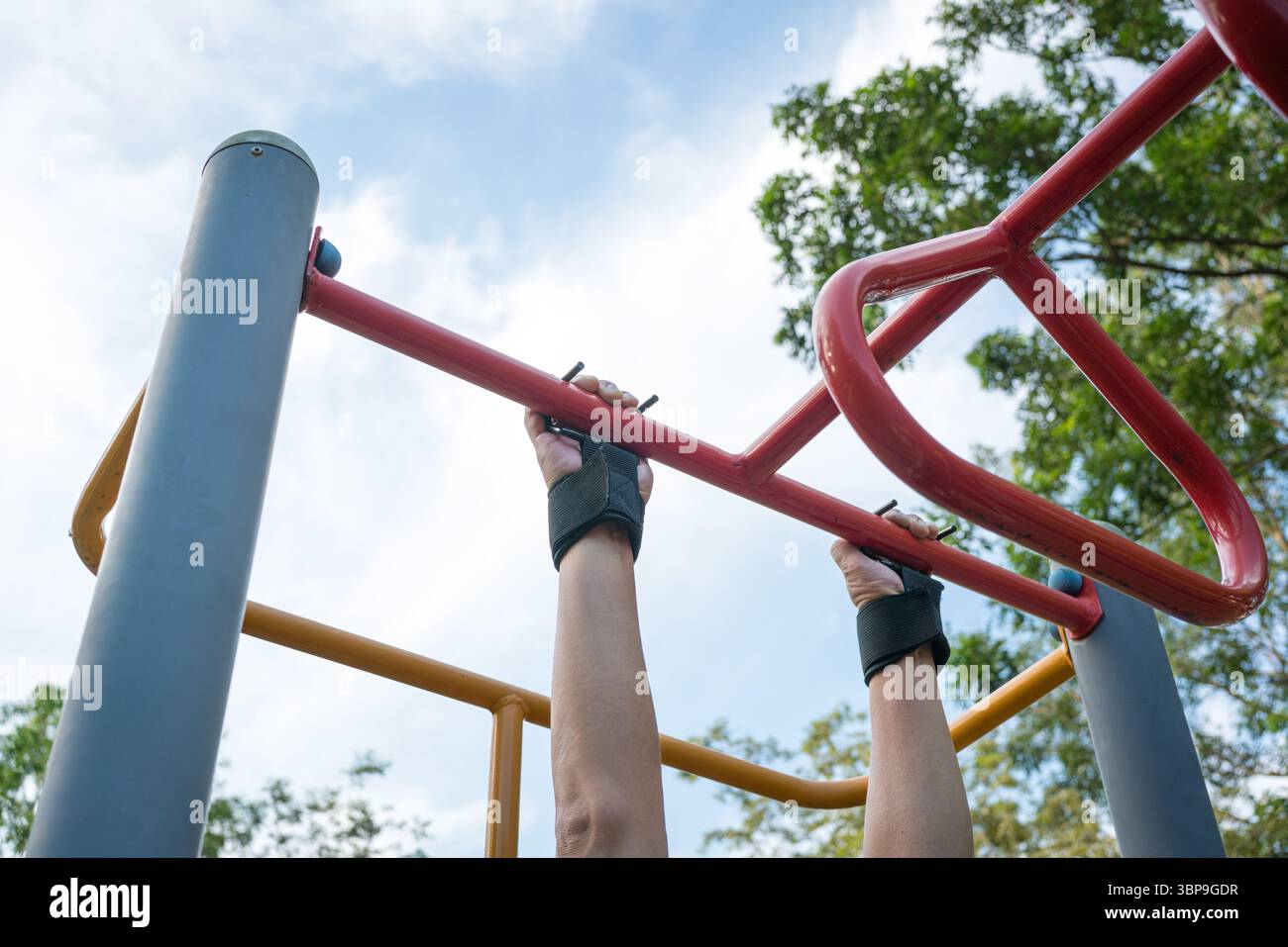 Uomo che si allena sulla barra d'acciaio utilizzando l'impugnatura da polso. Vista ad angolo basso. Foto Stock