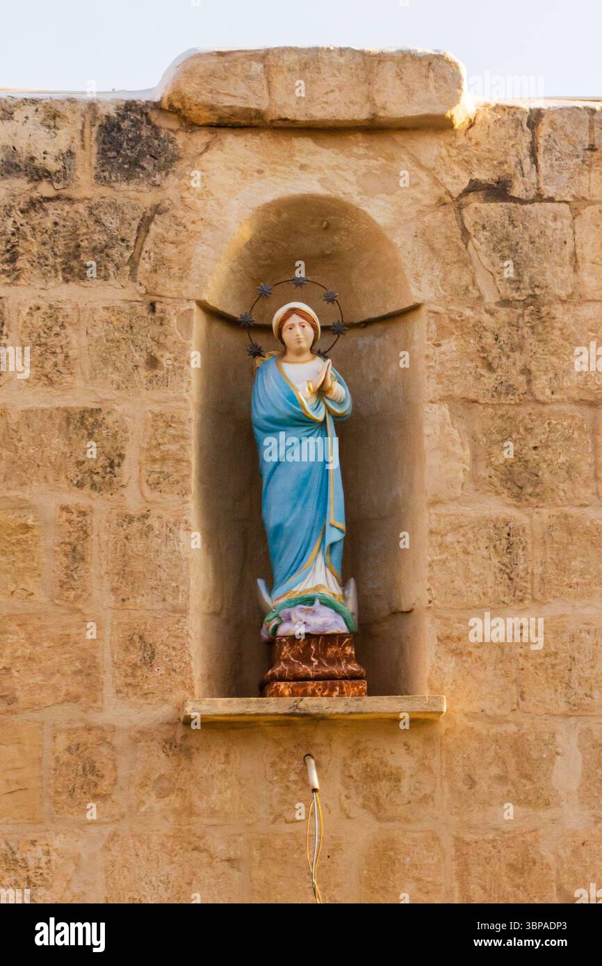 Statua della Vergine Maria in una nicchia di pietra con un alone Foto Stock