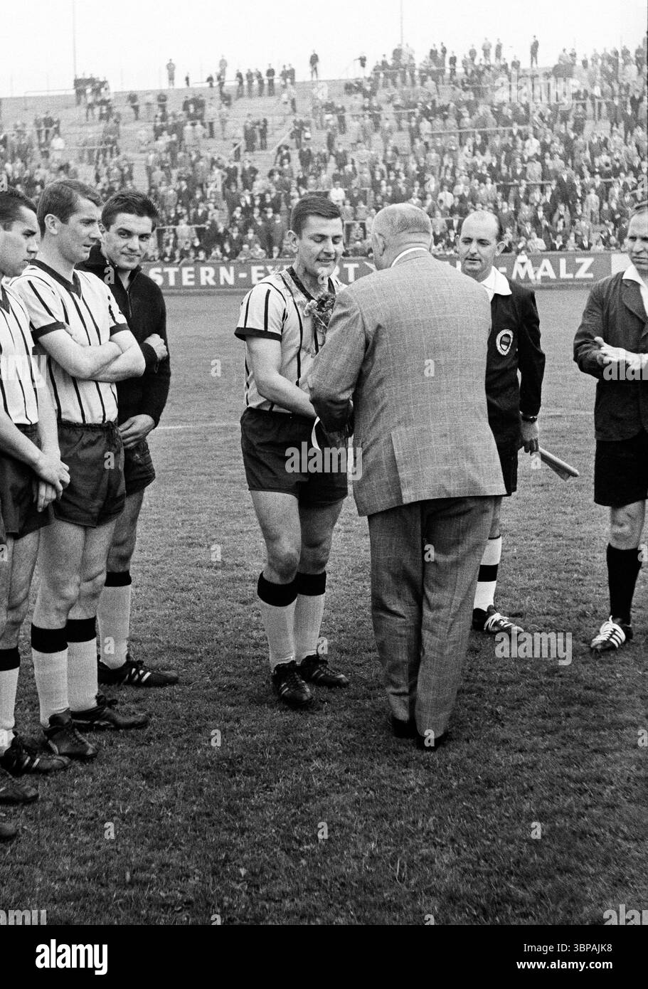 Sessant'anni, sport, calcio, Regionalliga West, 1964/1965, 16.05.1965, ETB Schwarz-Weiss Essen vs. Alemannia Aachen 2-2, Stadium Uhlenkrug di Essen, congratulazioni ai secondi classificati di Alemannia Aachen, Players f.l.t.r. Josef Thelen (Aquisgrana), Rainer Schoenwaelder (Aquisgrana), portiere Gerhard Prokop (Aquisgrana), capitano della squadra Christian Breuer (Aachen), arbitro destro) Foto Stock
