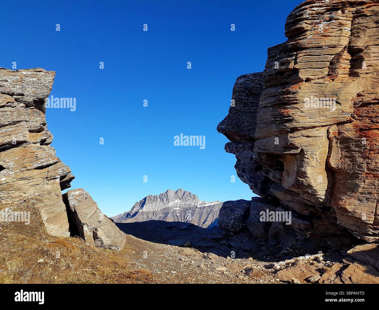Imponente formazione rocciosa a strati nell'alta montagna delle montagne svizzere con calda luce autunnale e scenografico sfondo montano Foto Stock