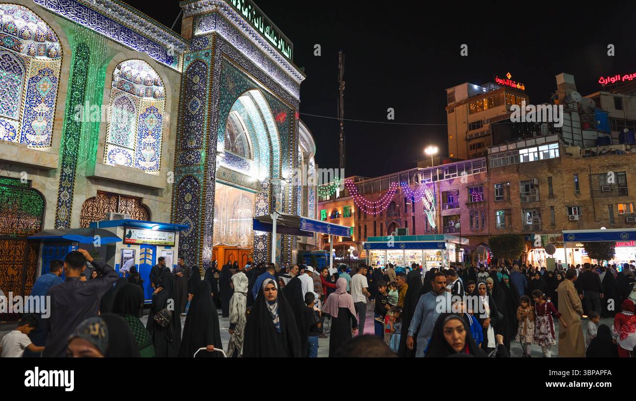 Persone di diversa provenienza riempiono le strade di Karbala, Iraq, godendosi feste serali e decorazioni vivaci. Foto Stock