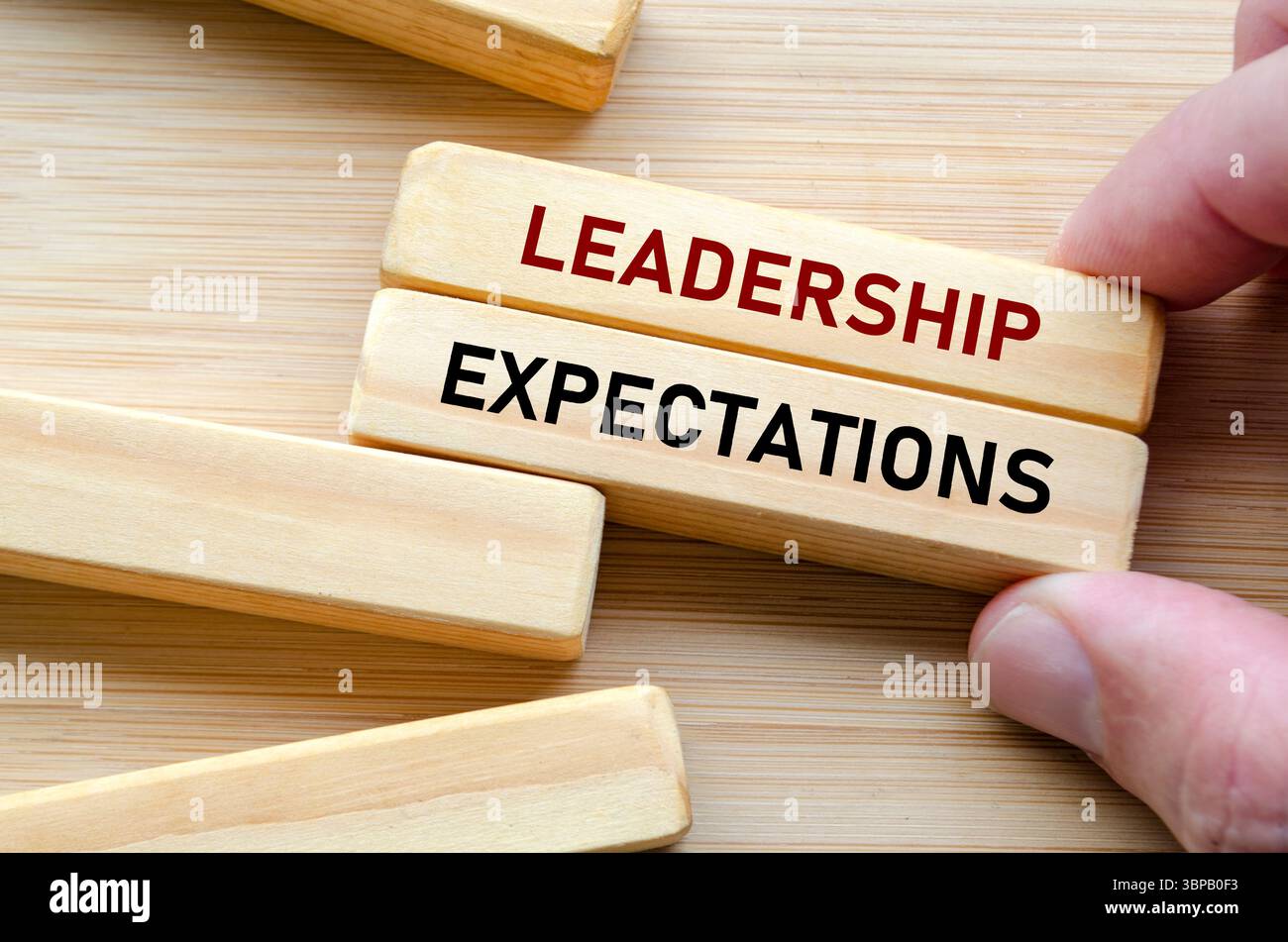 Messaggio di aspettativa della leadership su blocchi di legno tenuti a mano, simboleggiando la pressione e la responsabilità esercitate su coloro che assumono il comando in qualsiasi organizzazione Foto Stock