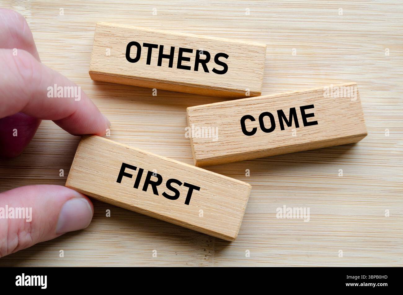 Altri vengono prima di tutto messaggio sui blocchi di legno, rafforzando l'idea che una leadership efficace implica servire e elevare gli altri in modo coerente. Foto Stock