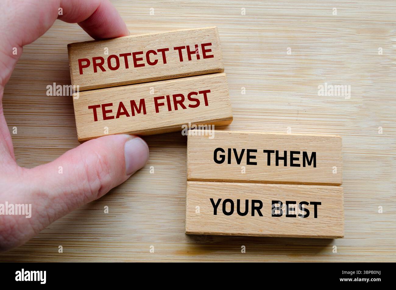 Proteggete prima il team e date loro il vostro testo migliore su blocchi di legno, rafforzando l'idea che una leadership efficace implica servire e migliorare Foto Stock