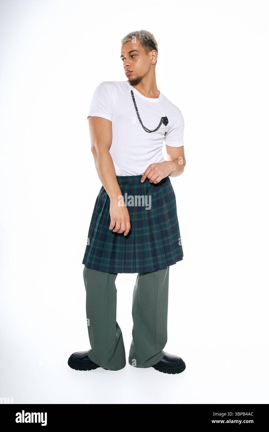 Un giovane uomo presenta scelte di moda uniche in uno studio luminoso, che unisce stile e stile. Foto Stock