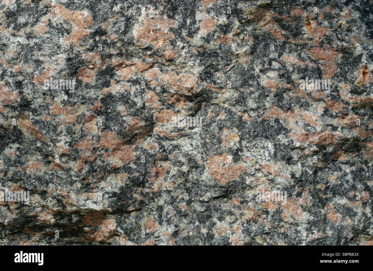 Consistenza del masso di granito marmorizzato rosso-nero. Pietra naturale come elemento paesaggistico. Copyspace. Foto Stock