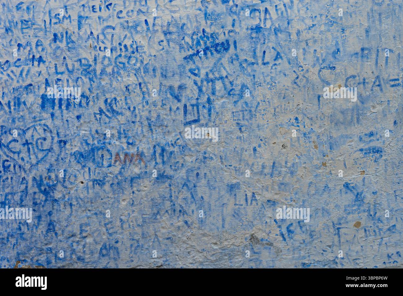 Graffiti blu e iscrizioni intemperie su una vecchia parete in gesso, Portogallo. Foto Stock