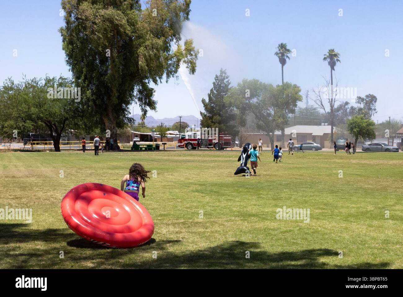 Il camion dei pompieri spruzza acqua sui bambini per divertirsi in estate al Parkview Park di Tucson, Arizona, una pausa fresca sotto il sole del deserto. Foto Stock