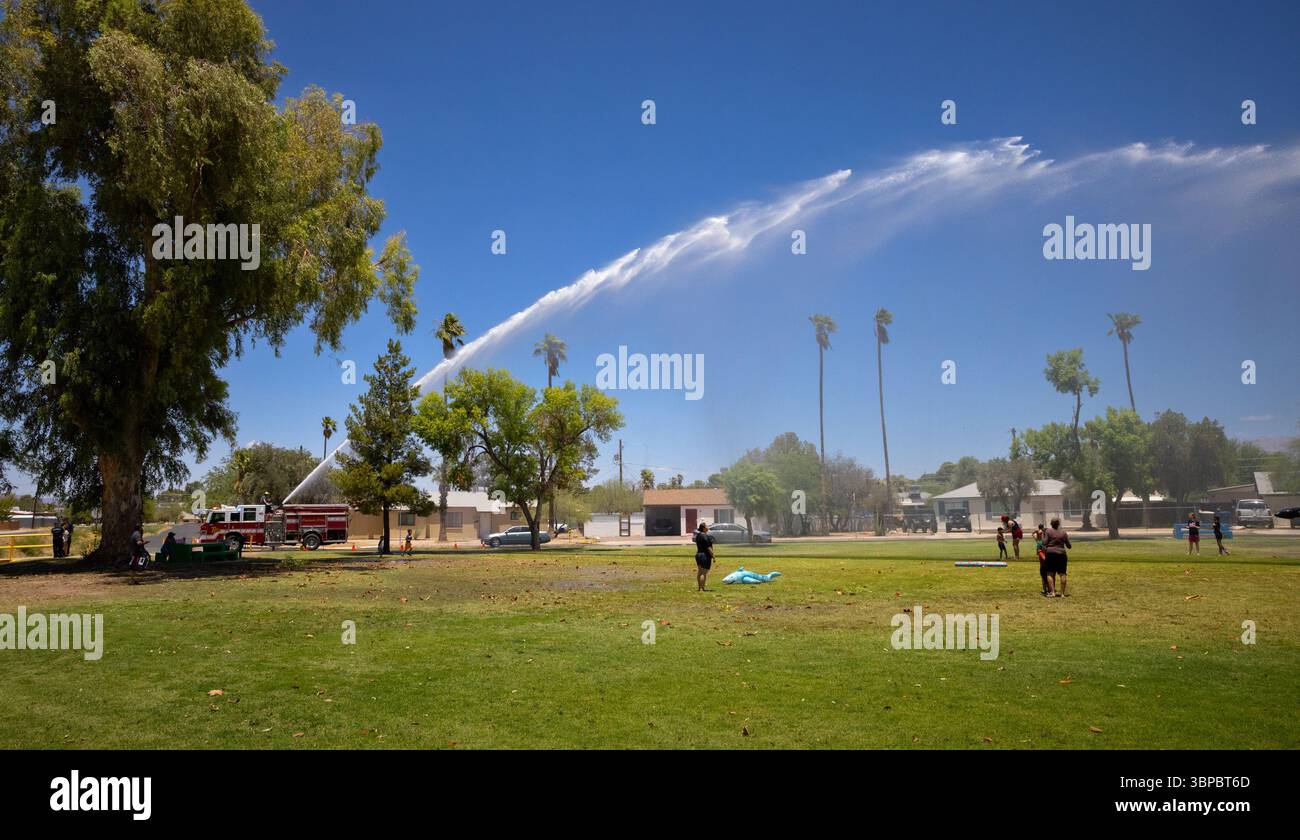 Il camion dei pompieri spruzza acqua sui bambini per divertirsi in estate al Parkview Park di Tucson, Arizona, una pausa fresca sotto il sole del deserto. Foto Stock