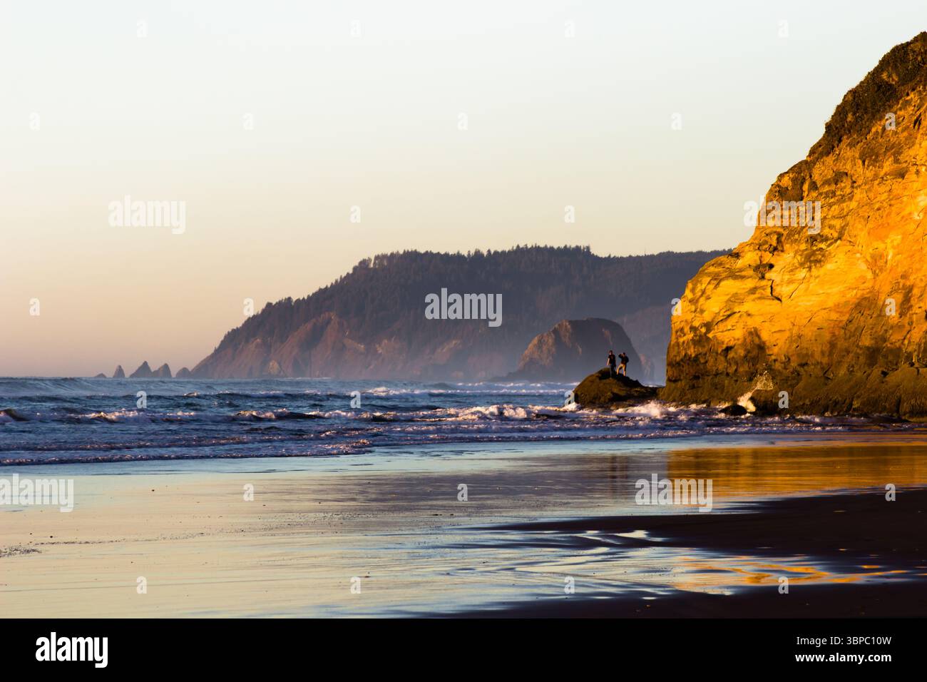 Hug Point State Park, Oregon - 28 novembre 2015: Due persone si stagliano su una formazione rocciosa, godendo la vista dell'Oceano Pacifico e dell'Oregon. Foto Stock