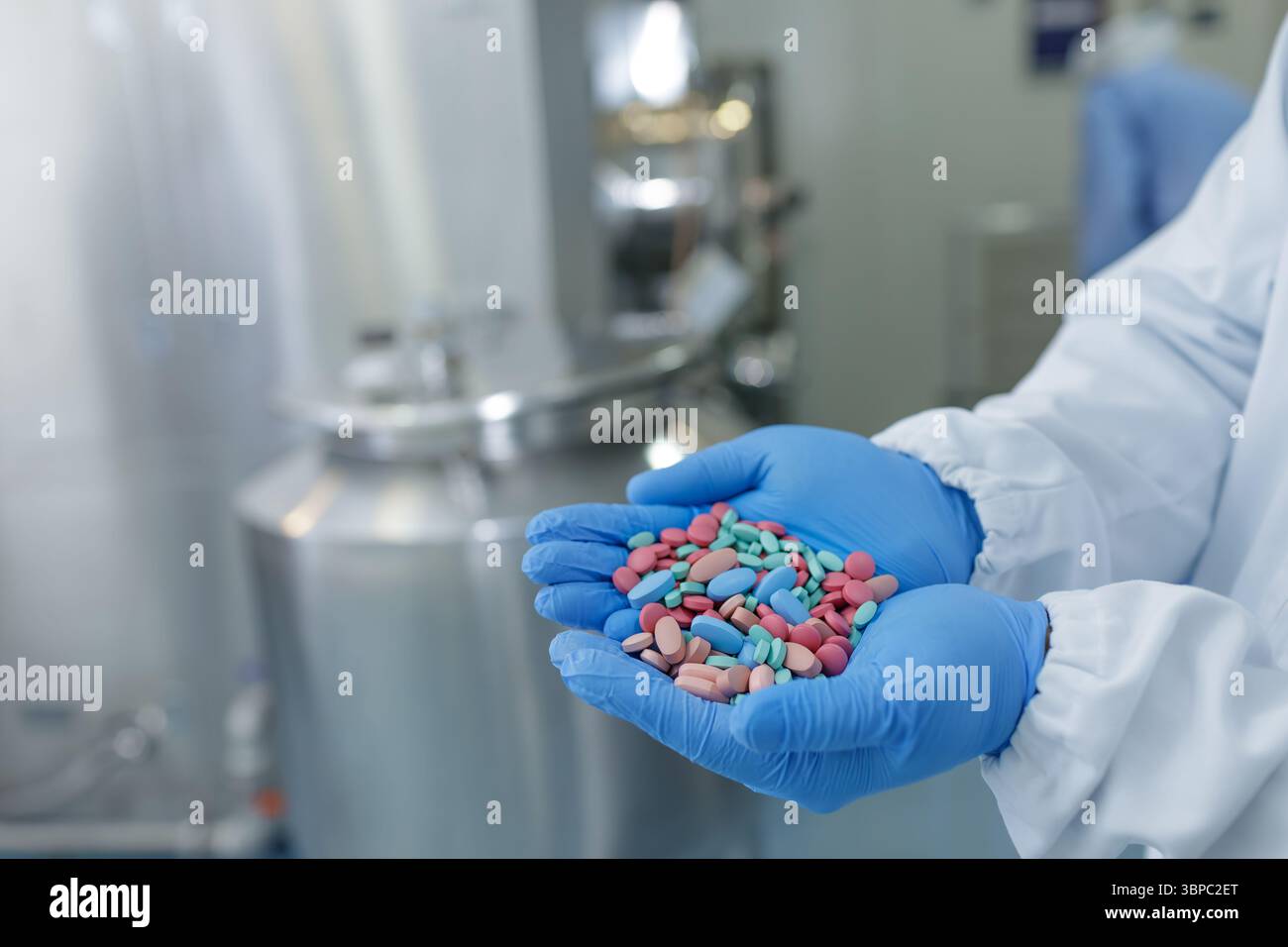 I guanti tengono le pillole assortite in un moderno impianto farmaceutico, evidenziando la produzione avanzata di farmaci e la sicurezza Foto Stock