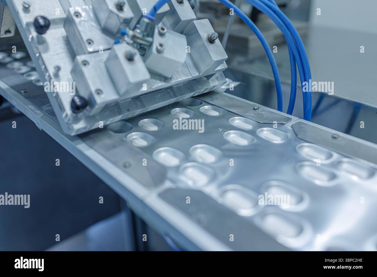 Primo piano del processo di confezionamento automatizzato dei tablet in una moderna fabbrica farmaceutica, evidenziando la produzione avanzata nel settore sanitario Foto Stock