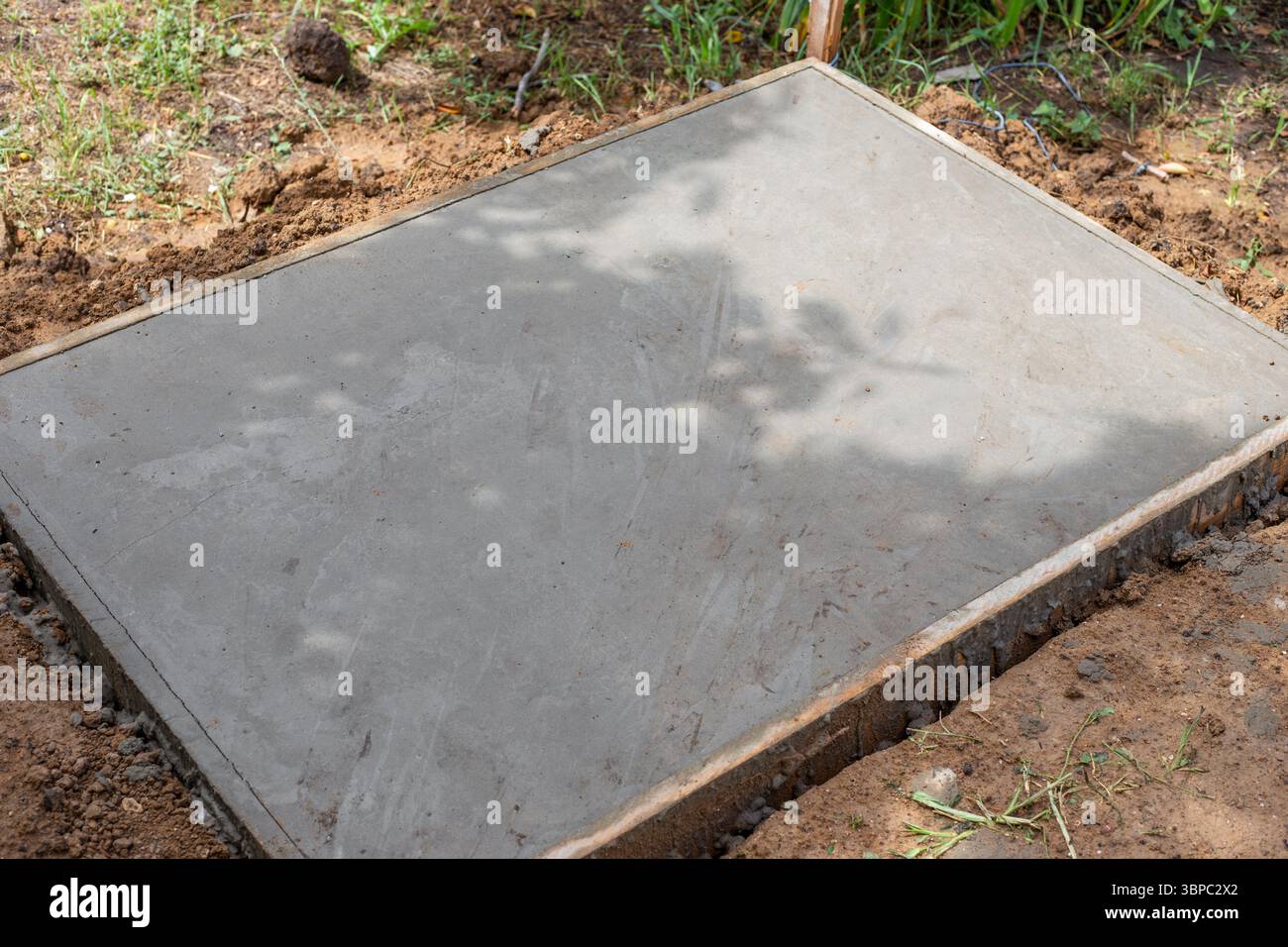 Soletta in calcestruzzo appena versata, superficie liscia e piana, incorniciata in legno, si appoggia al suolo. Costruzione di fondazioni. Foto Stock