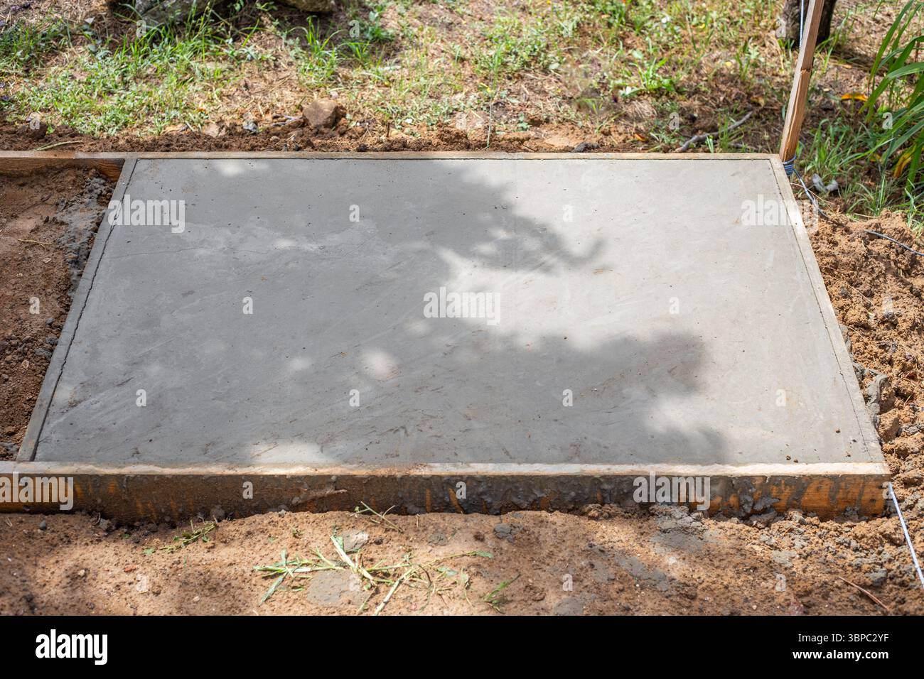 Soletta in calcestruzzo appena versata, superficie liscia e piana, incorniciata in legno, si appoggia al suolo. Costruzione di fondazioni. Foto Stock