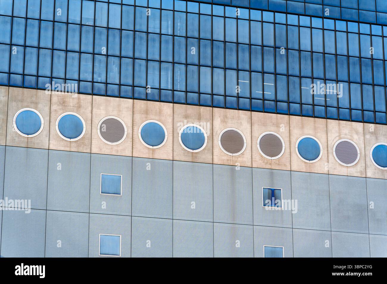 Edificio architettonico moderno e artistico che utilizza finestre circolari e quadrate per creare un design ritmico e futuristico della facciata Foto Stock
