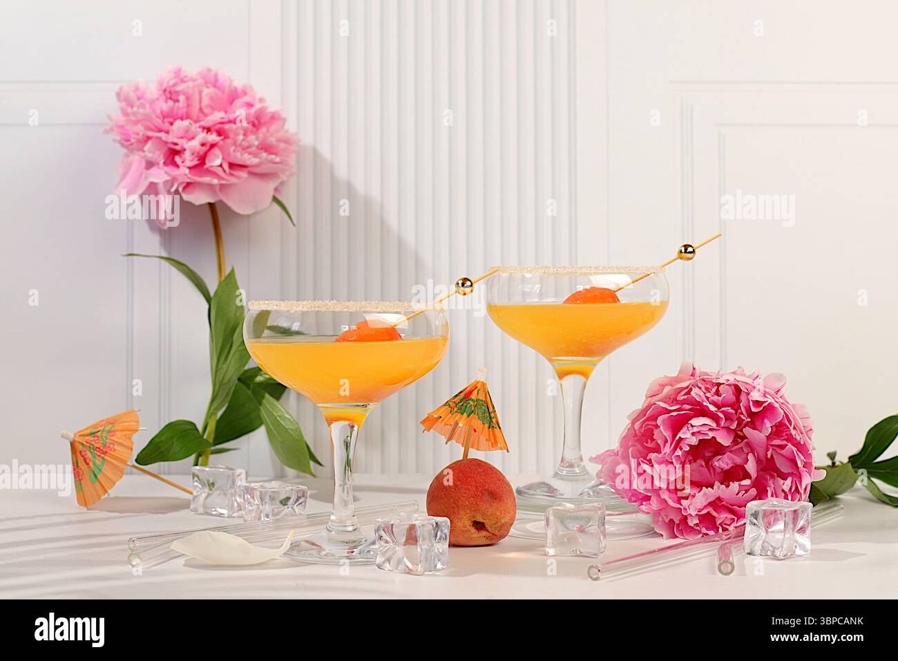 Natura morta moderna con punch di ghiaccio con albicocche, cocktail alcolico estivo per feste e peonie su un moderno sfondo soleggiato, concetto minimalista per bar Foto Stock