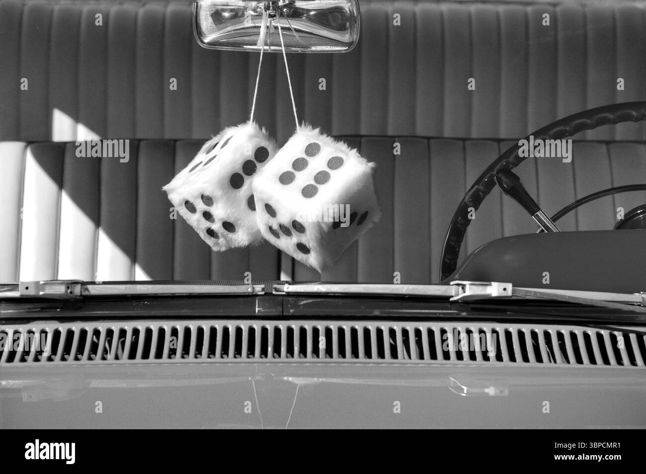 Dadi sfocati appesi in bianco e nero sullo specchietto retrovisore di un'auto d'epoca Foto Stock