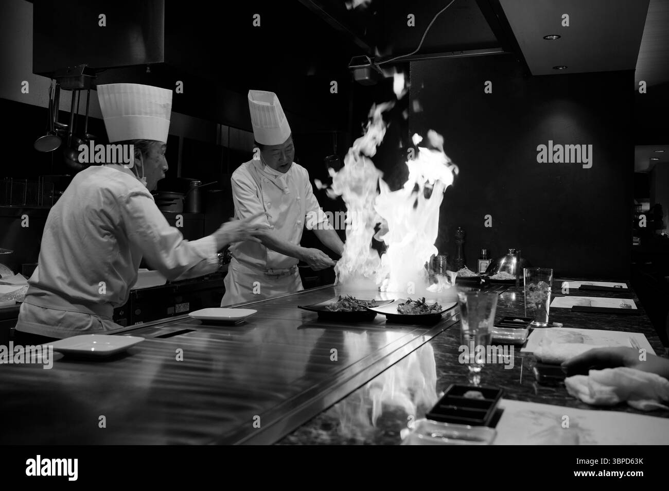 Gli chef Teppanyaki a Tokyo intrattengono i commensali con fiamme spettacolari sulla griglia, mostrando precisione, abilità e la classica ospitalità giapponese Foto Stock