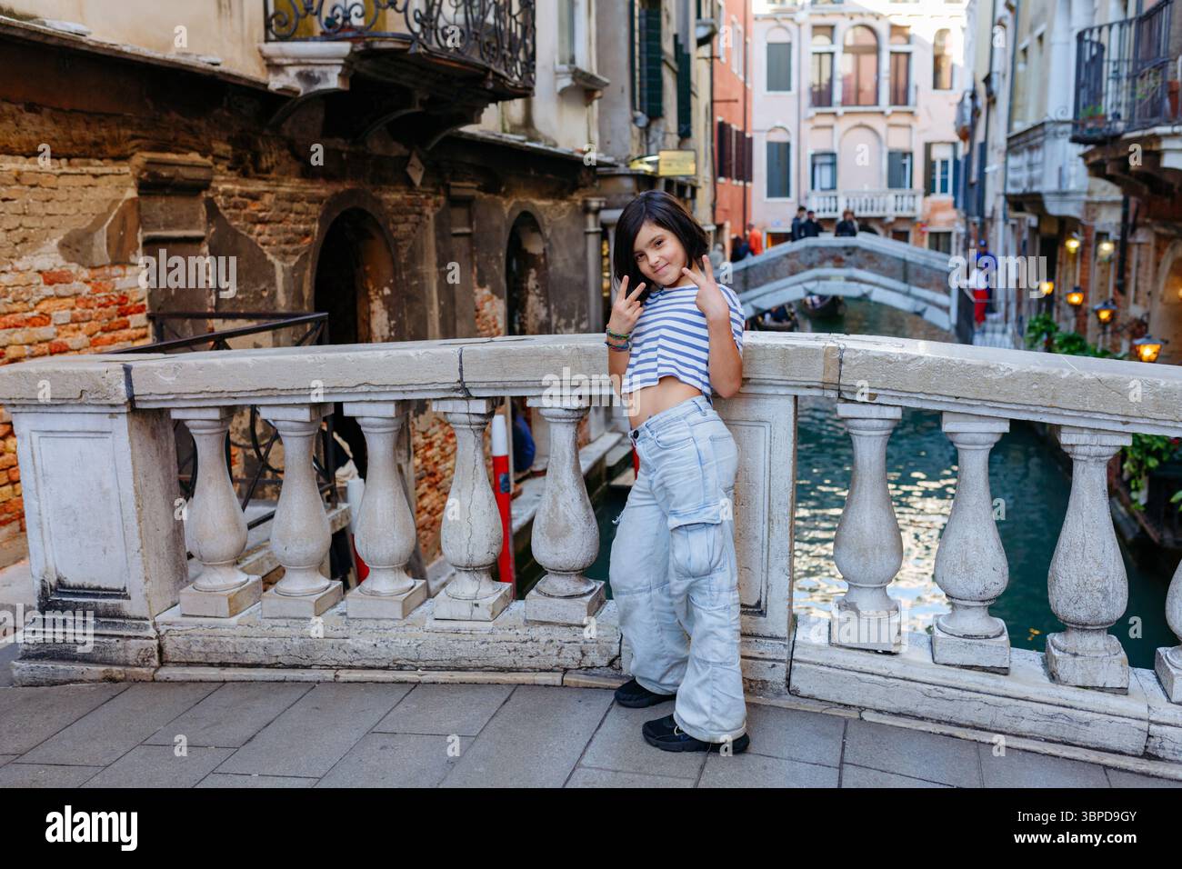 Una ragazza felice in piedi di fronte a uno dei canali di Venezia che viaggia in Italia in posa per una foto Foto Stock