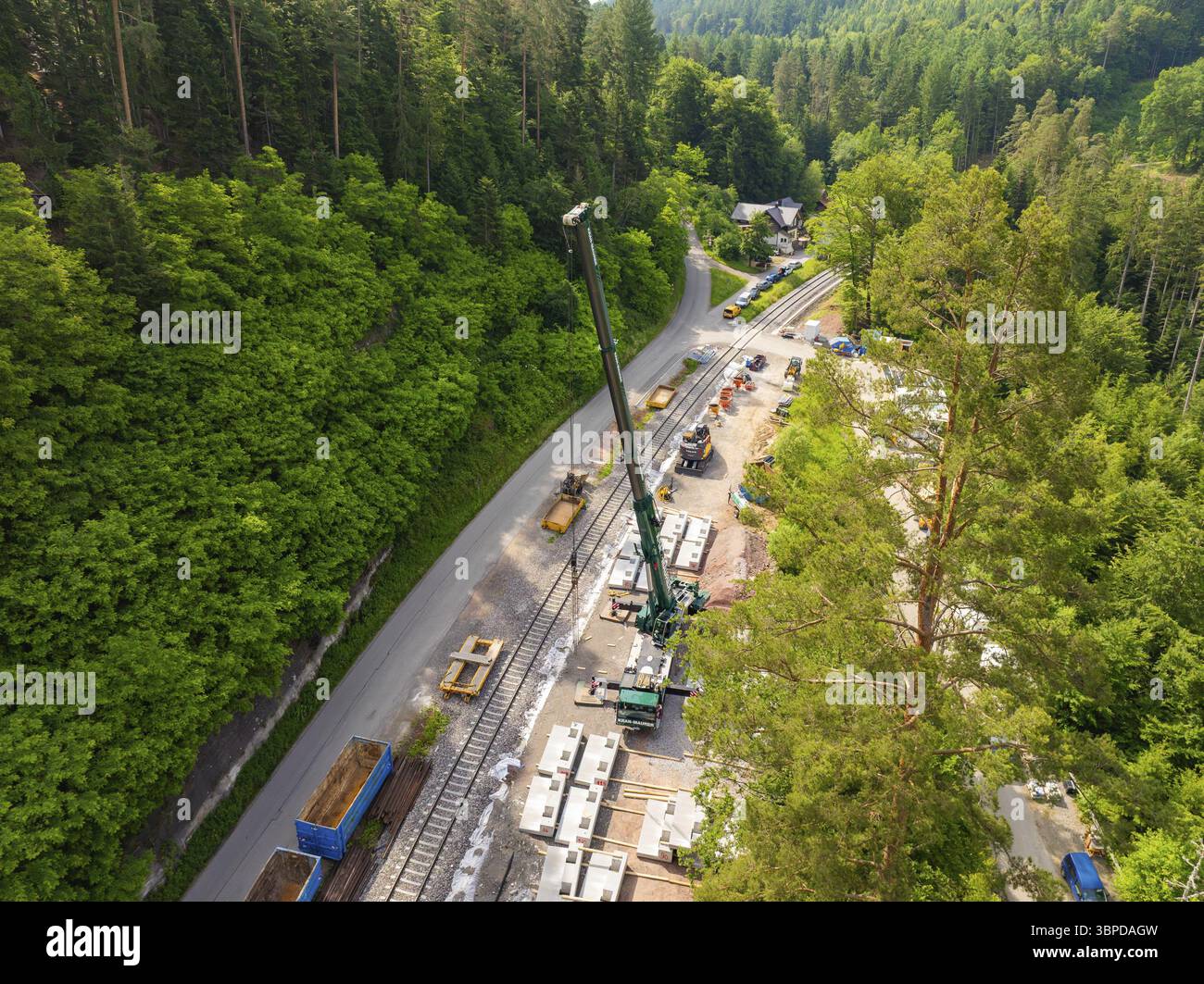Lavori di costruzione con una gru lungo i binari ferroviari, circondati dalla foresta, costruzione della ferrovia Hermann Hesse, Calw, Germania, Europa Foto Stock