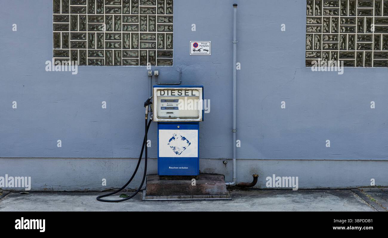 Un'unica pompa di benzina storica di fronte a un muro blu Foto Stock