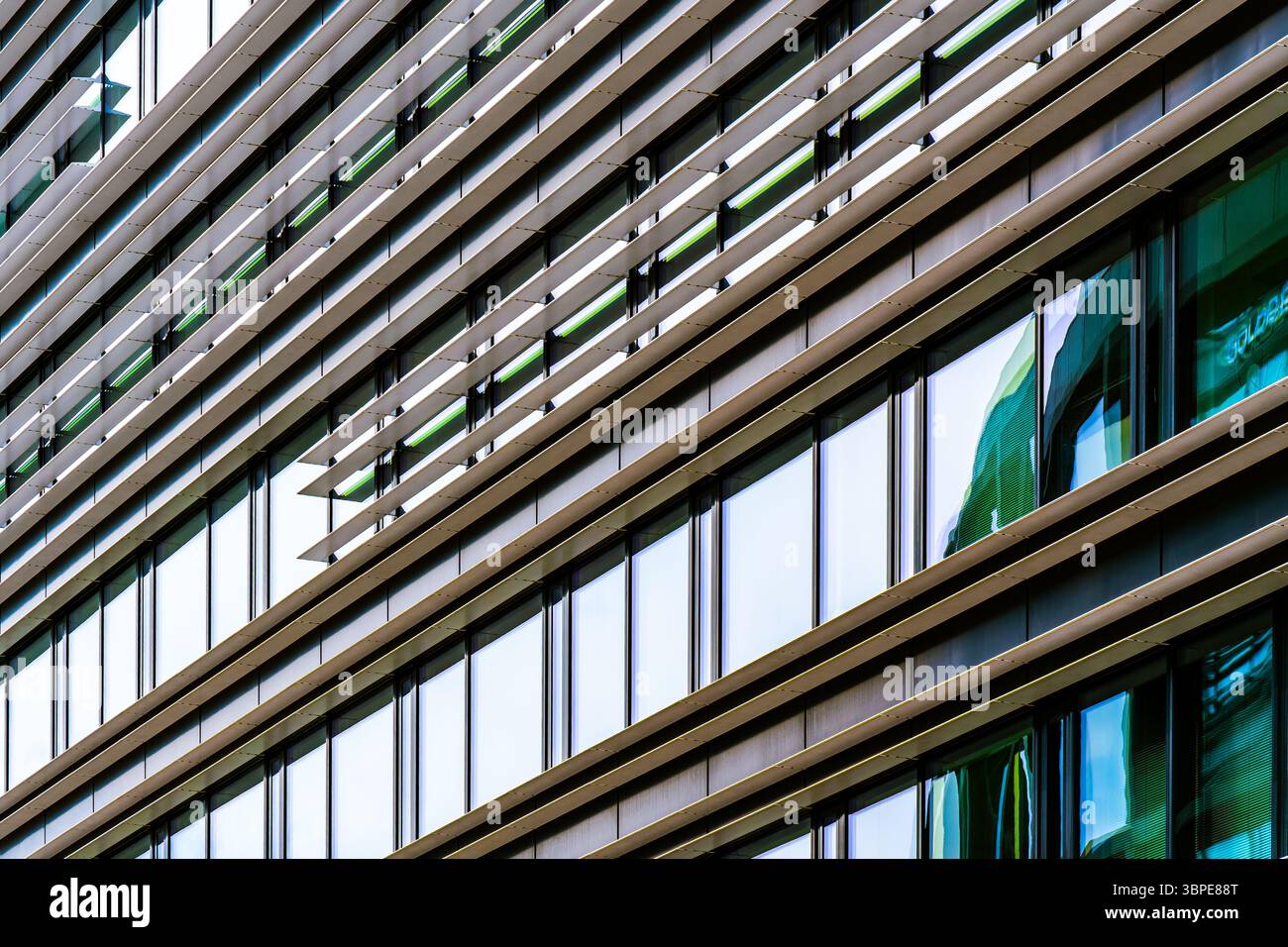 Facciata moderna con alette metalliche orizzontali e finestre in vetro riflettente che formano un motivo diagonale a strati Foto Stock