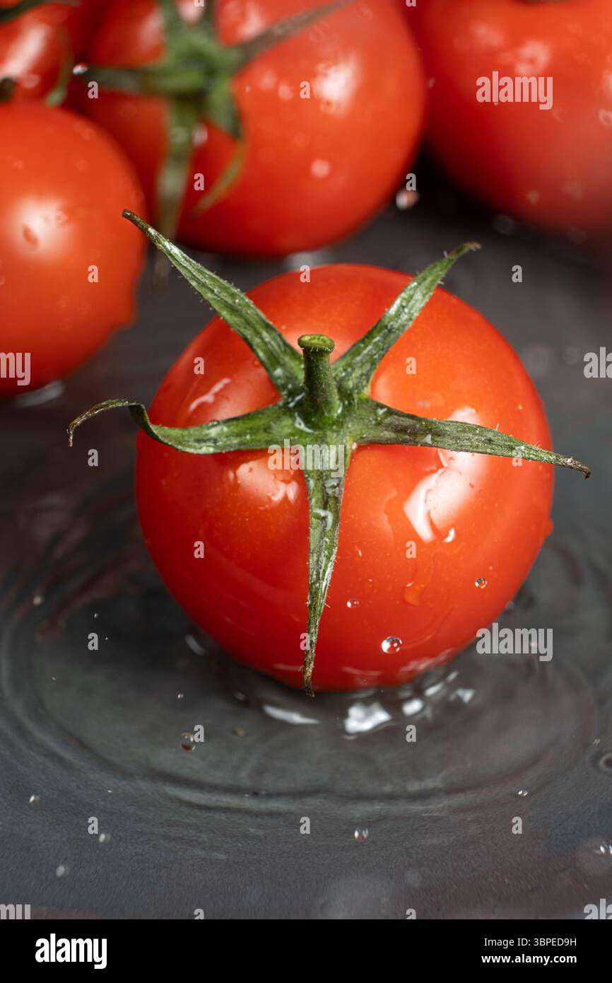 Portare i pomodori interi in una spruzzata d'acqua. Foto Stock