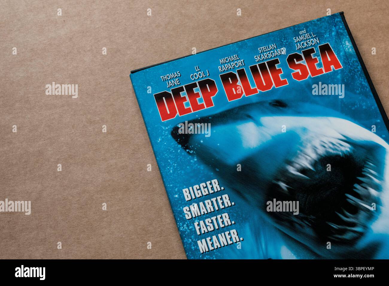 Copertina DVD Deep Blue Sea con squalo, attori principali e parole "Bigger. Più intelligente. Più veloce. Più cattivo." isolato su fondo di cartone. Foto Stock