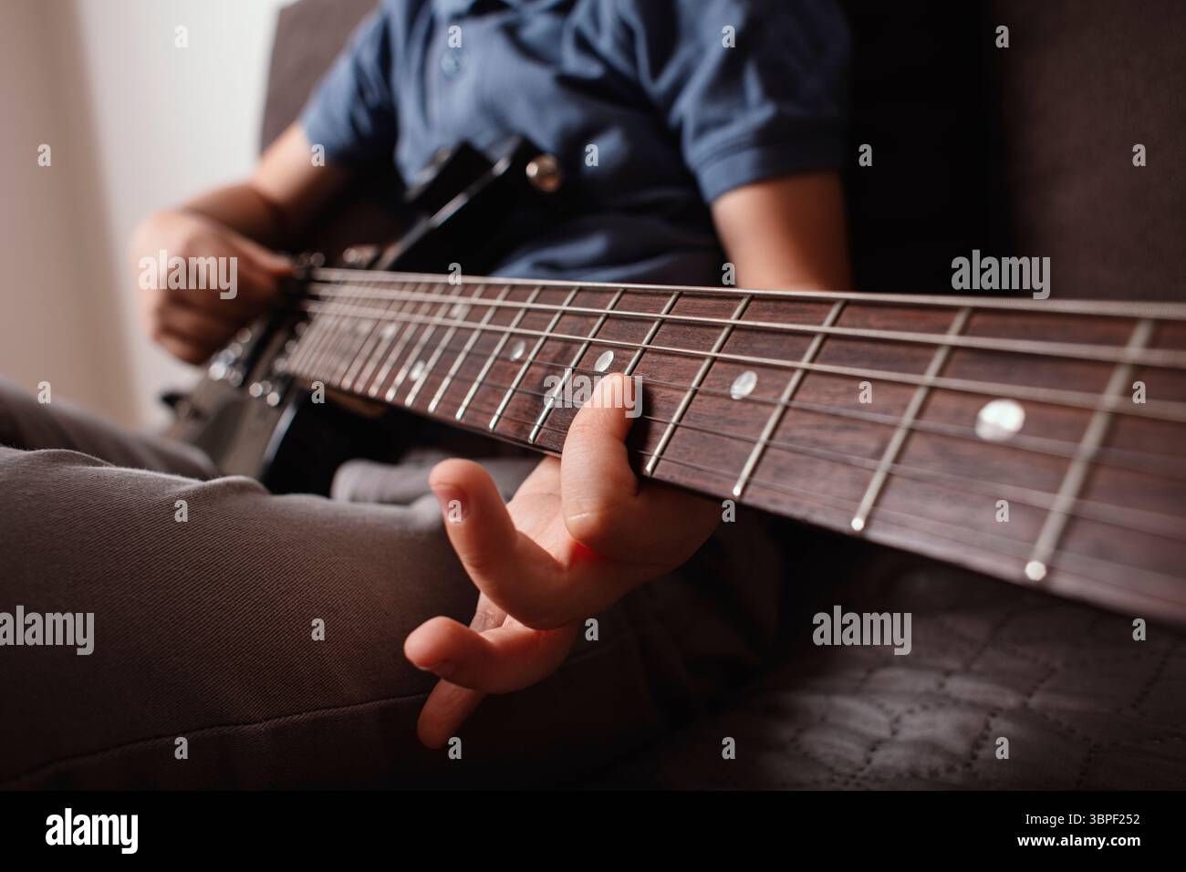 Primo piano della mano di un bambino che suona la chitarra elettrica. Concentratevi sulle corde di chitarra e sul fretboard. Concetto di musica, apprendimento, talento. Foto Stock