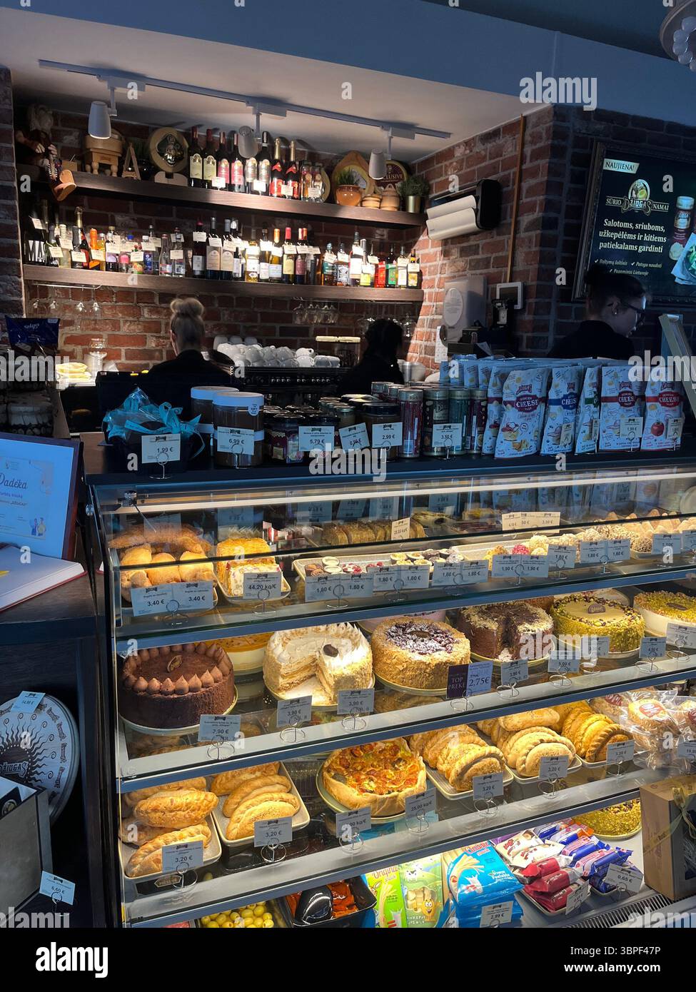 Un affascinante angolo caffetteria che presenta un'allettante esposizione di dolci colorati, torte cremose e irresistibili pasticcini dietro il bicchiere. - Immagine stock catturata con smartphone