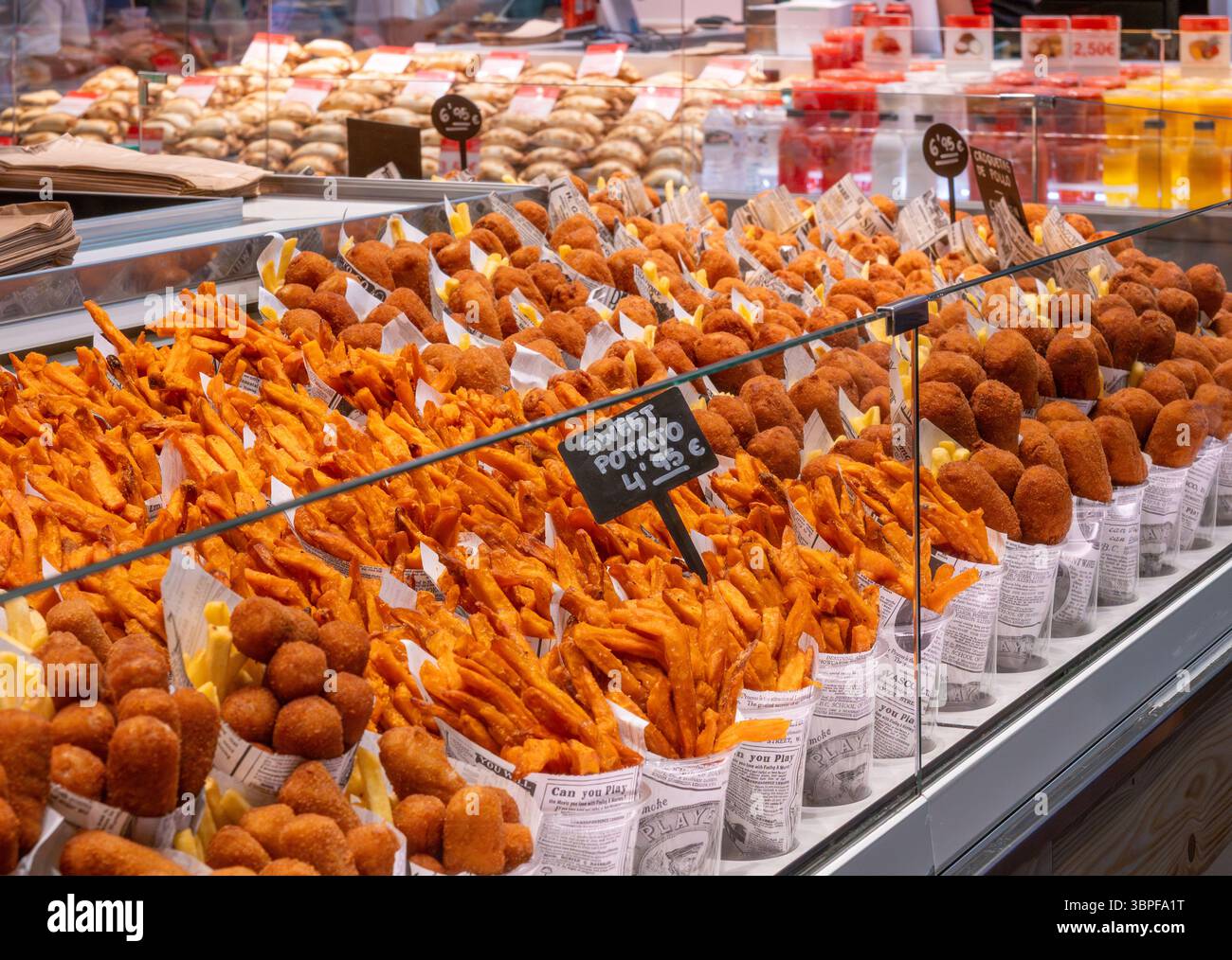 Coni di carta di patatine fritte calde e dolci e crocchette fritte in mostra presso una bancarella di tapas nel mercato la Boqueria, Barcellona, Spagna. Foto Stock