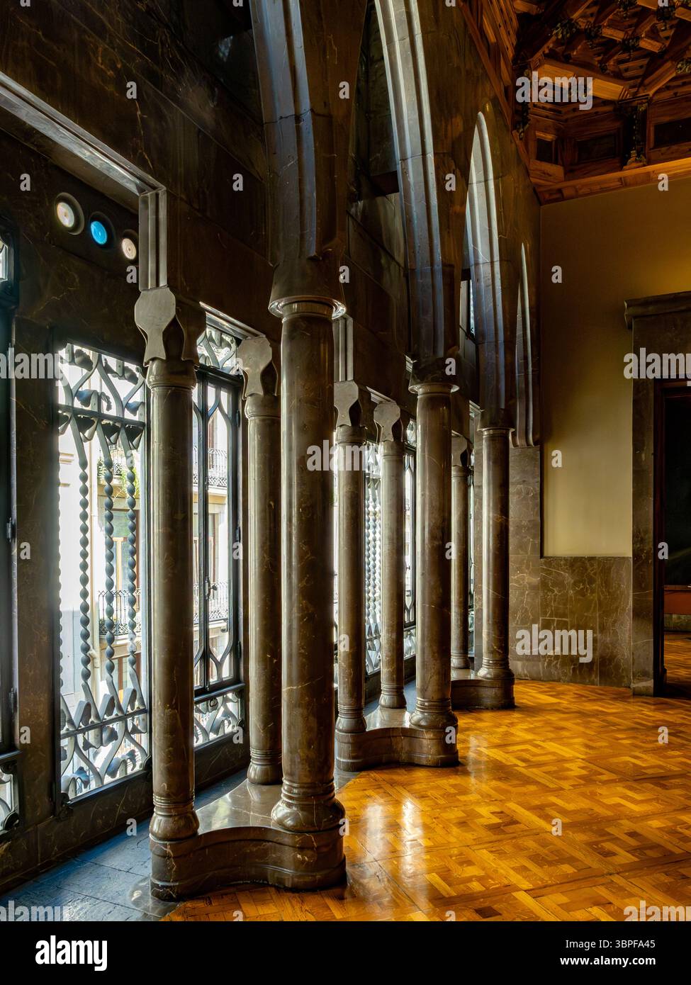 Le colonne in marmo lucido si riflettono sul pavimento in parquet della grande sala del Palau Güell, un capolavoro in stile Art Nouveau di Gaudí a Barcellona, Spagna. Foto Stock