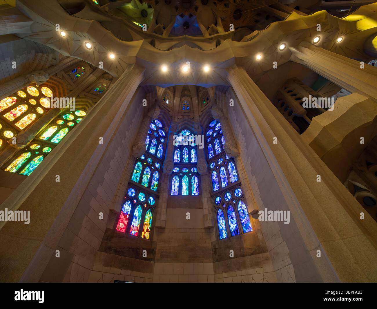 Le magnifiche e moderne vetrate colorate si illuminano di luce blu e verde all'interno della Sagrada Familia di Antoni Gaudí, Barcellona, Spagna. Foto Stock