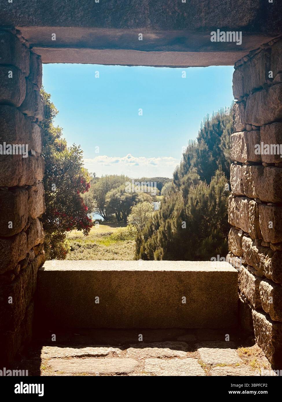 Antica arcata in pietra che incornicia un paesaggio rurale illuminato dal sole di colline e alberi nella regione di Porto, Portogallo, rovine storiche e campagna panoramica Foto Stock
