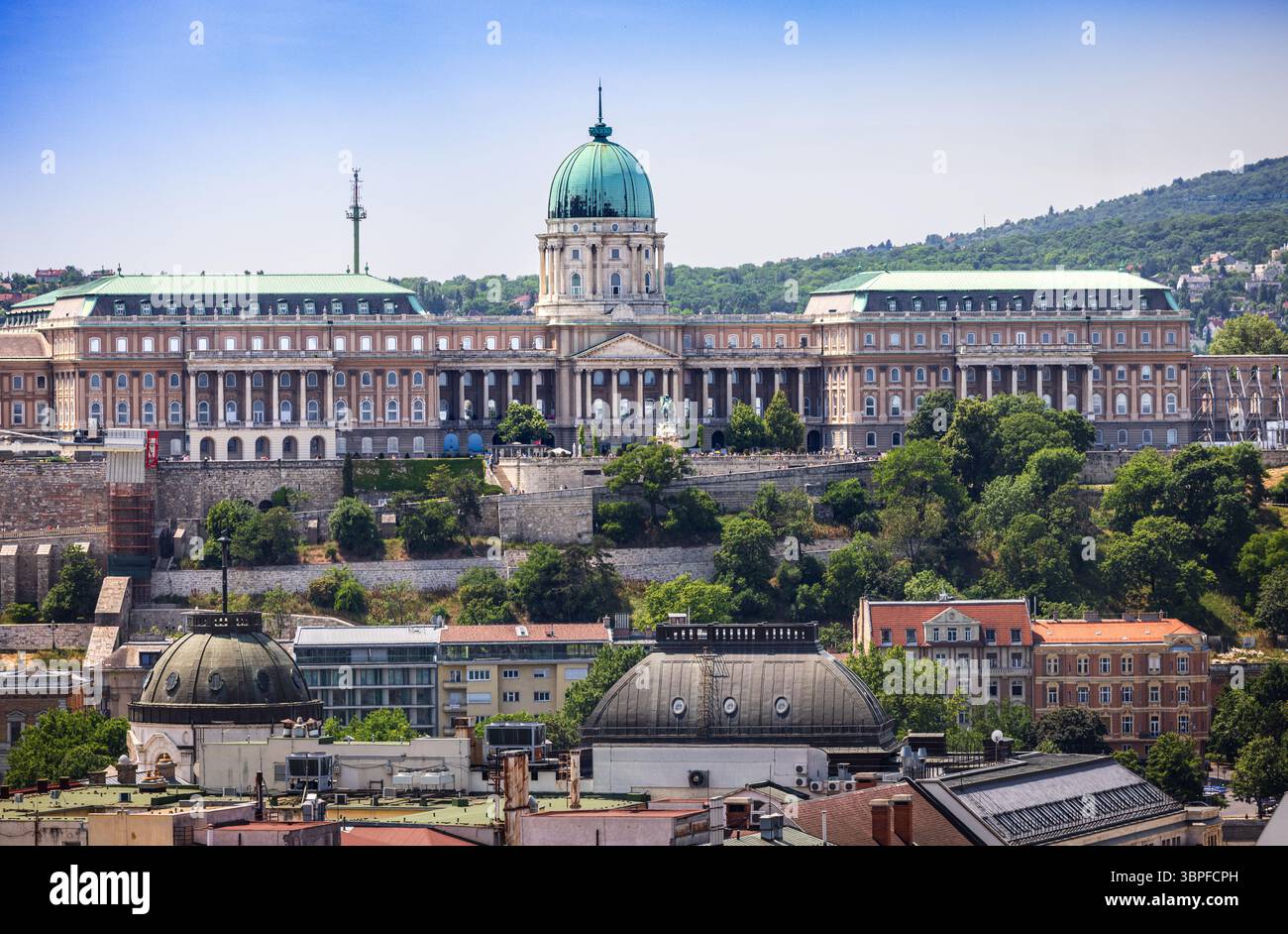 Vista panoramica del Castello di Buda con la sua cupola verde e la facciata neoclassica, circondato da lussureggianti colline Foto Stock