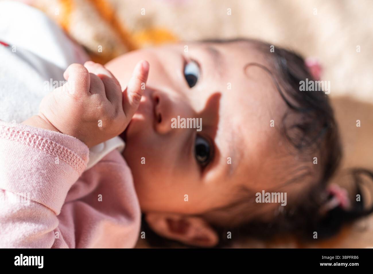 Un simpatico bambino indonesiano in abiti caldi adagiato su una coperta colorata Foto Stock
