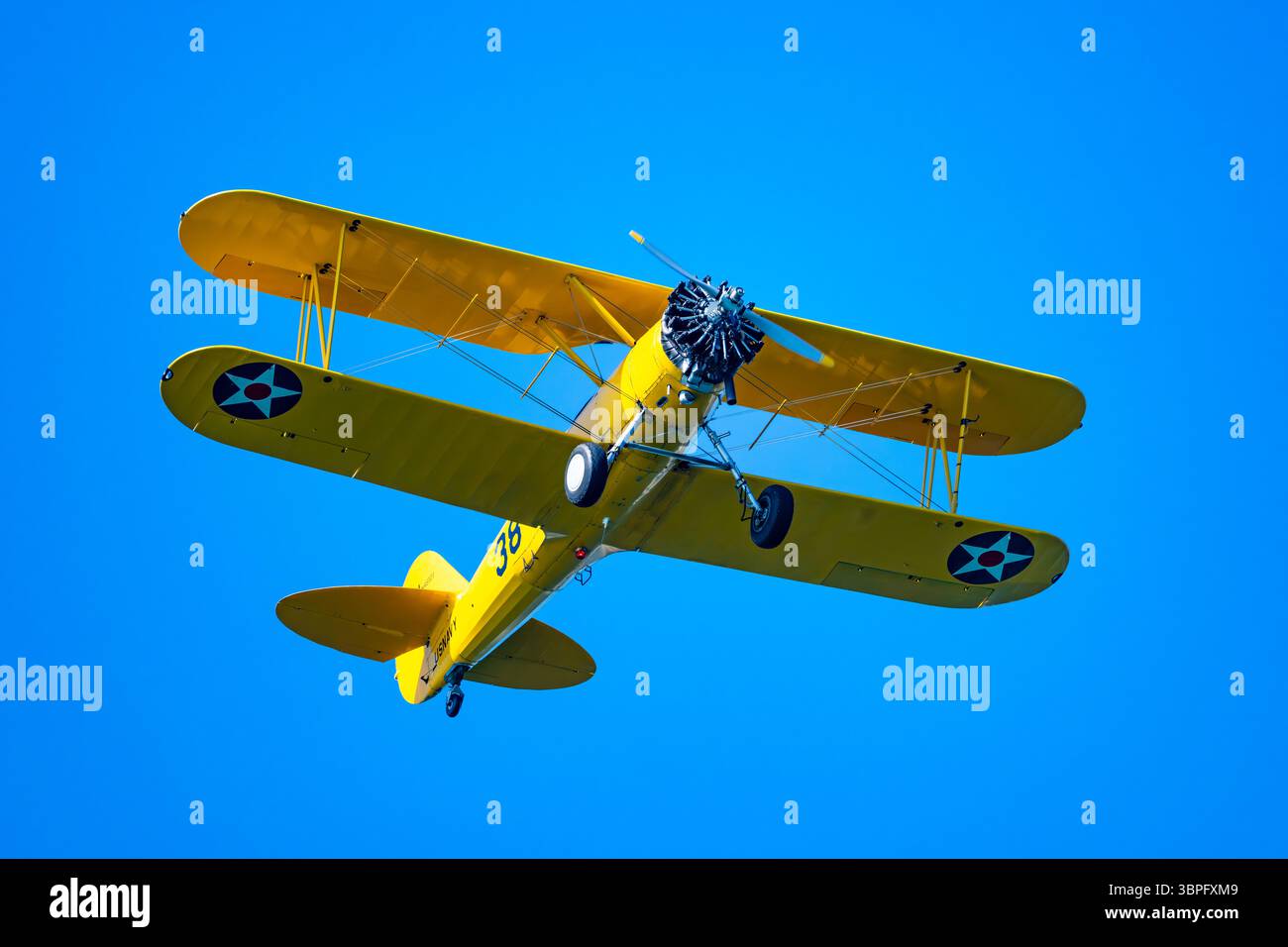 Un biplano giallo brillante Boeing Stearman che vola nel cielo blu. California, Stati Uniti. Foto Stock