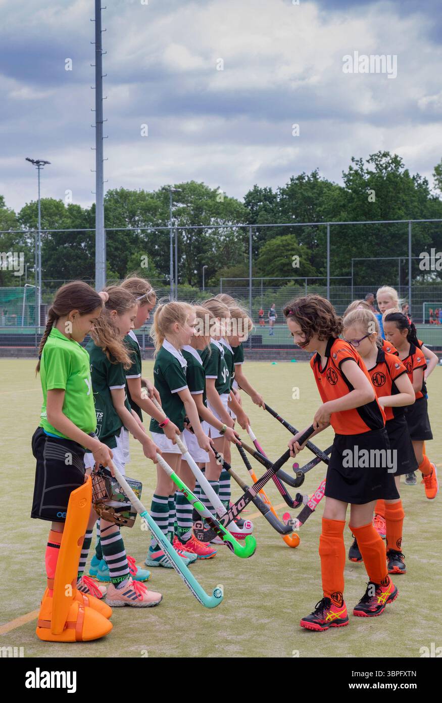 Paesi Bassi, i bambini giocheranno una partita di hockey e si augureranno una partita piacevole prima colpendo i bastoncini da hockey contro ogni altra Foto Stock
