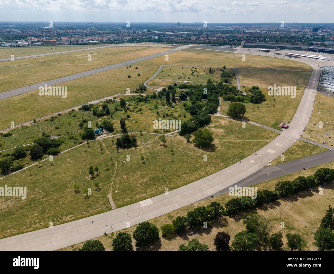 Vista aerea della vasta distesa di Tempelhofer Feld con le piste che attraversano il verde, creando un netto contrasto tra natura e cemento, Berlino, Berlino, Germania. Foto Stock
