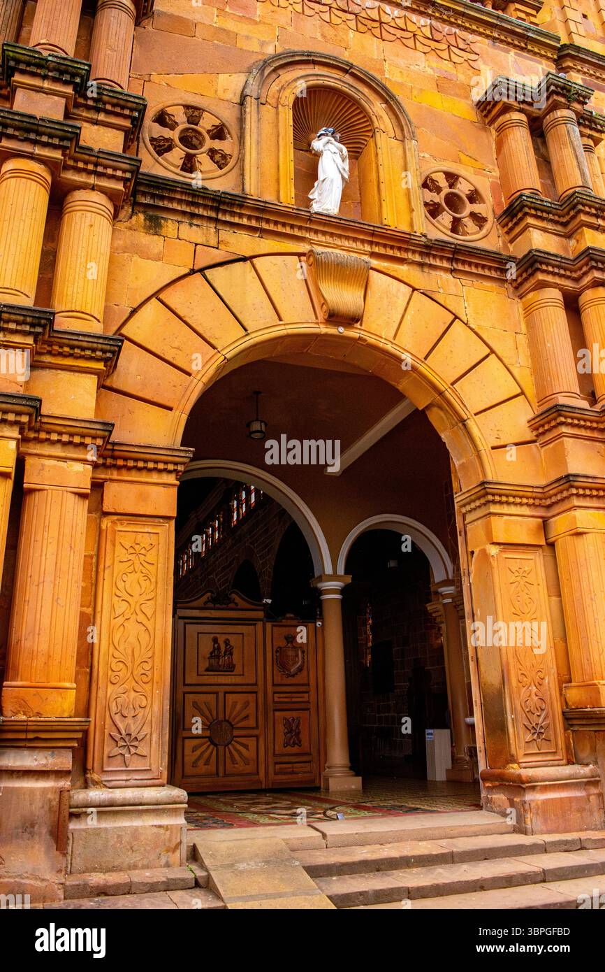 Un primo piano dell'ingresso ornato di una chiesa storica a Barichara, Santander, che mostra una splendida architettura e colori vivaci. Foto Stock