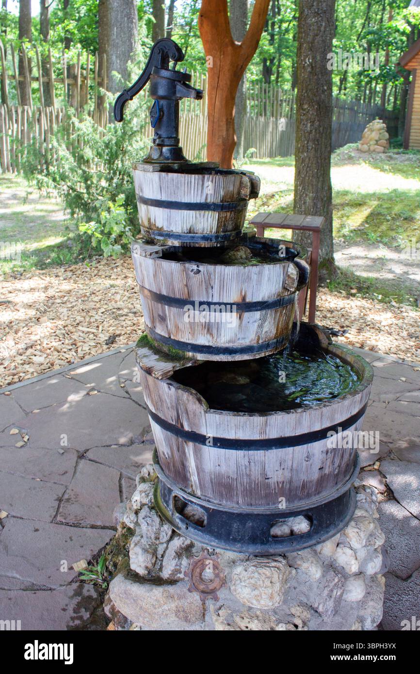 Fontana in giardino a più livelli. Design rustico con giochi d'acqua in giardino. L'acqua che scorre da un contenitore di legno all'altro crea un suono rilassante. Foto Stock