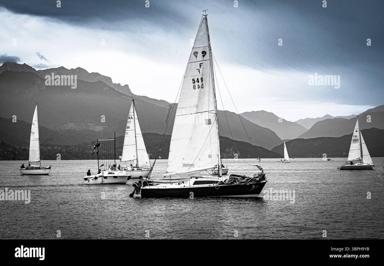In tarda giornata, barche a vela sul lago di Annecy, nella foresta alpina delle suggestive alpi con case, chiese e hotel che punteggiano l'ecoregione delle Alpi Foto Stock