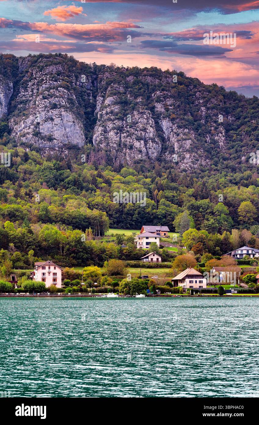 Case tradizionali, chiese e hotel punteggiano l'ecoregione delle conifere delle Alpi e delle foreste miste sulle rive del lago di Annecy in Francia Foto Stock