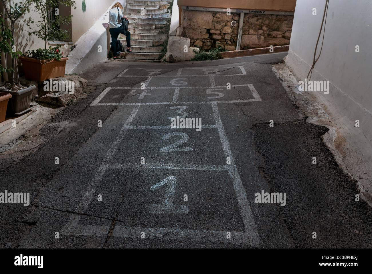Donna accanto a Hopscotch che disegna nella Urban Athens Alley Foto Stock