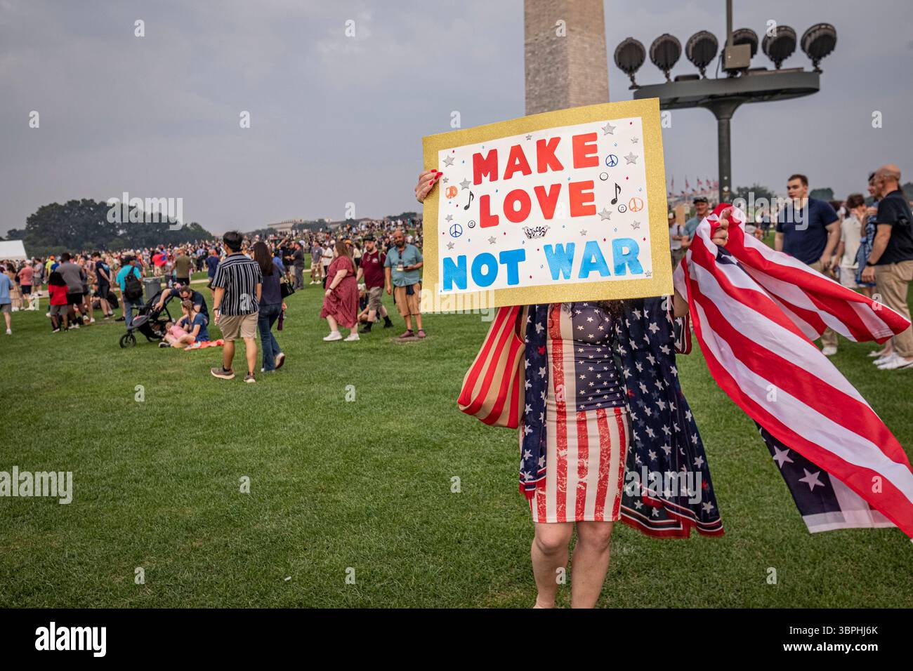 Washington DC - Una donna tiene un cartello "Make Love Not War" durante la parata del 14 giugno 2025 per il 250° anniversario dell'esercito statunitense, che includeva una gara di fitness mattutina, mostre di carri armati, elicotteri e armi storiche sul National Mall, una dimostrazione di paracadute e un finale di fuochi d'artificio. Lo stesso giorno, che è stato anche il 79 ° compleanno del presidente Trump, le proteste hanno avuto luogo a livello nazionale sotto la bandiera dei "No Kings" contro le politiche dell'amministrazione. Foto Stock