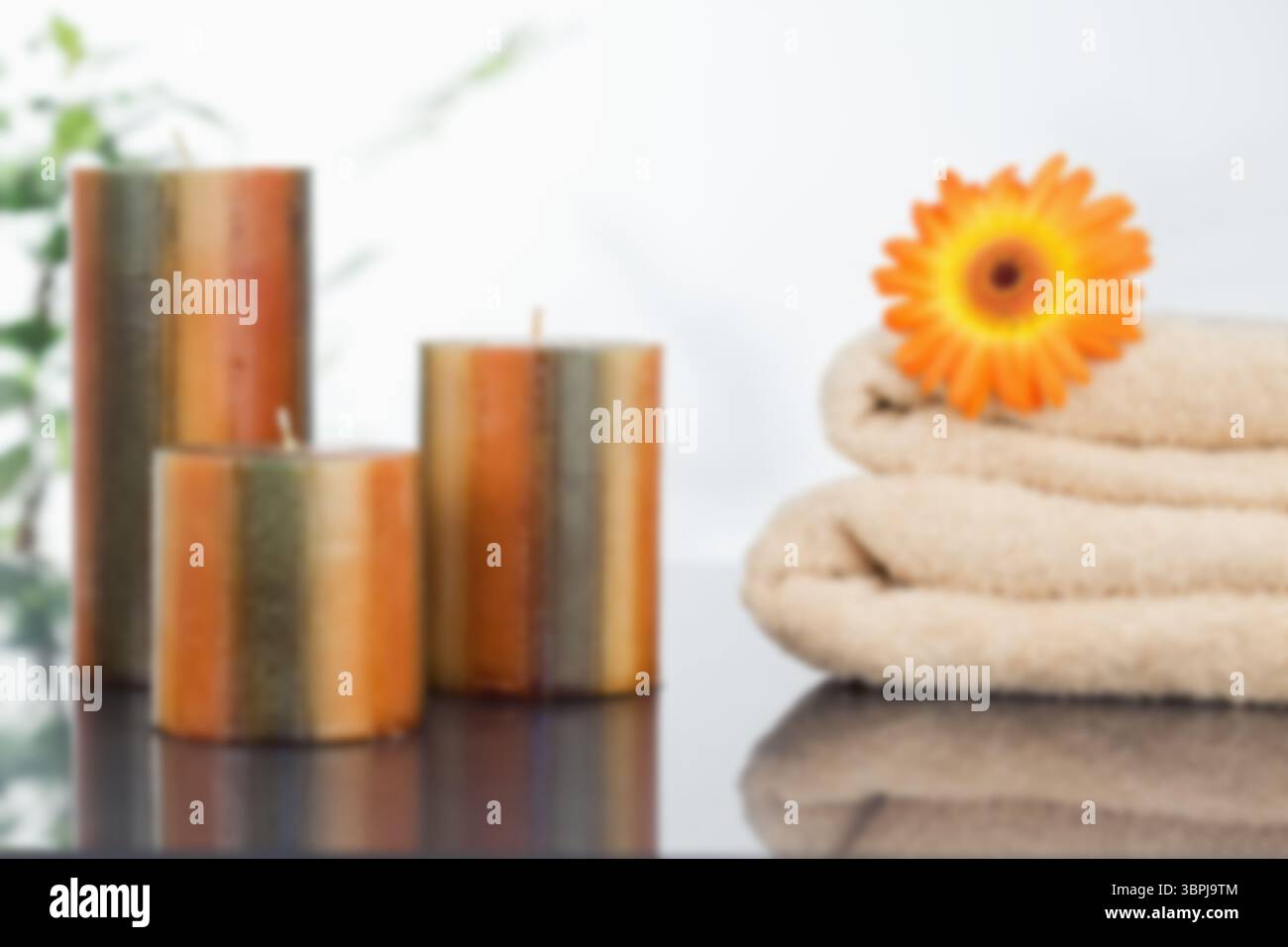 Candele con margherita Gerbera arancia su asciugamano Foto Stock
