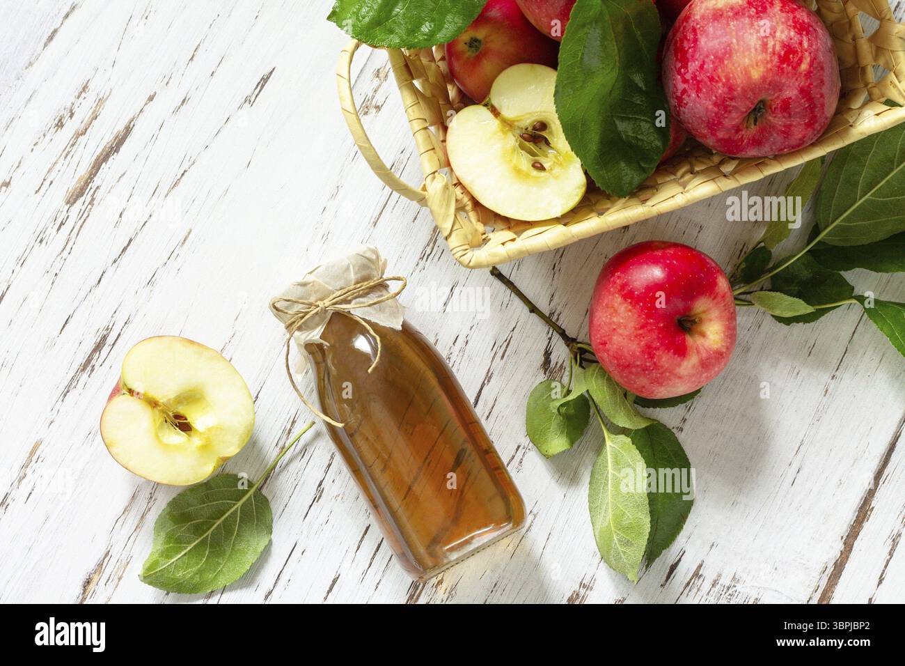 Cibo biologico sano. Aceto di mele, una bottiglia di aceto di sidro di mele su un tavolo rustico. Sfondo piatto della vista superiore Foto Stock