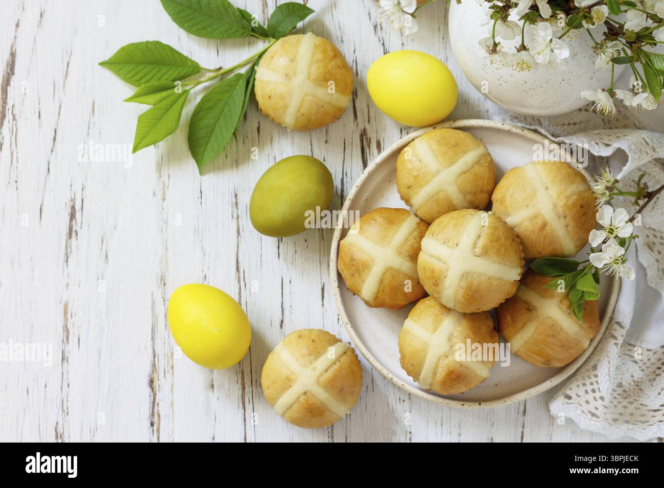 Felice Pasqua cibo festivo concetto. Tradizionale croci pasquali caldi fatti in casa con uva passa e uova pasquali colorate naturali su un tavolo rustico. Vista dall'alto Foto Stock Felice Pasqua cibo festivo concetto. Tradizionale croci pasquali caldi fatti in casa con uva passa e uova pasquali colorate naturali su un tavolo rustico. Vista dall'alto Foto Stock