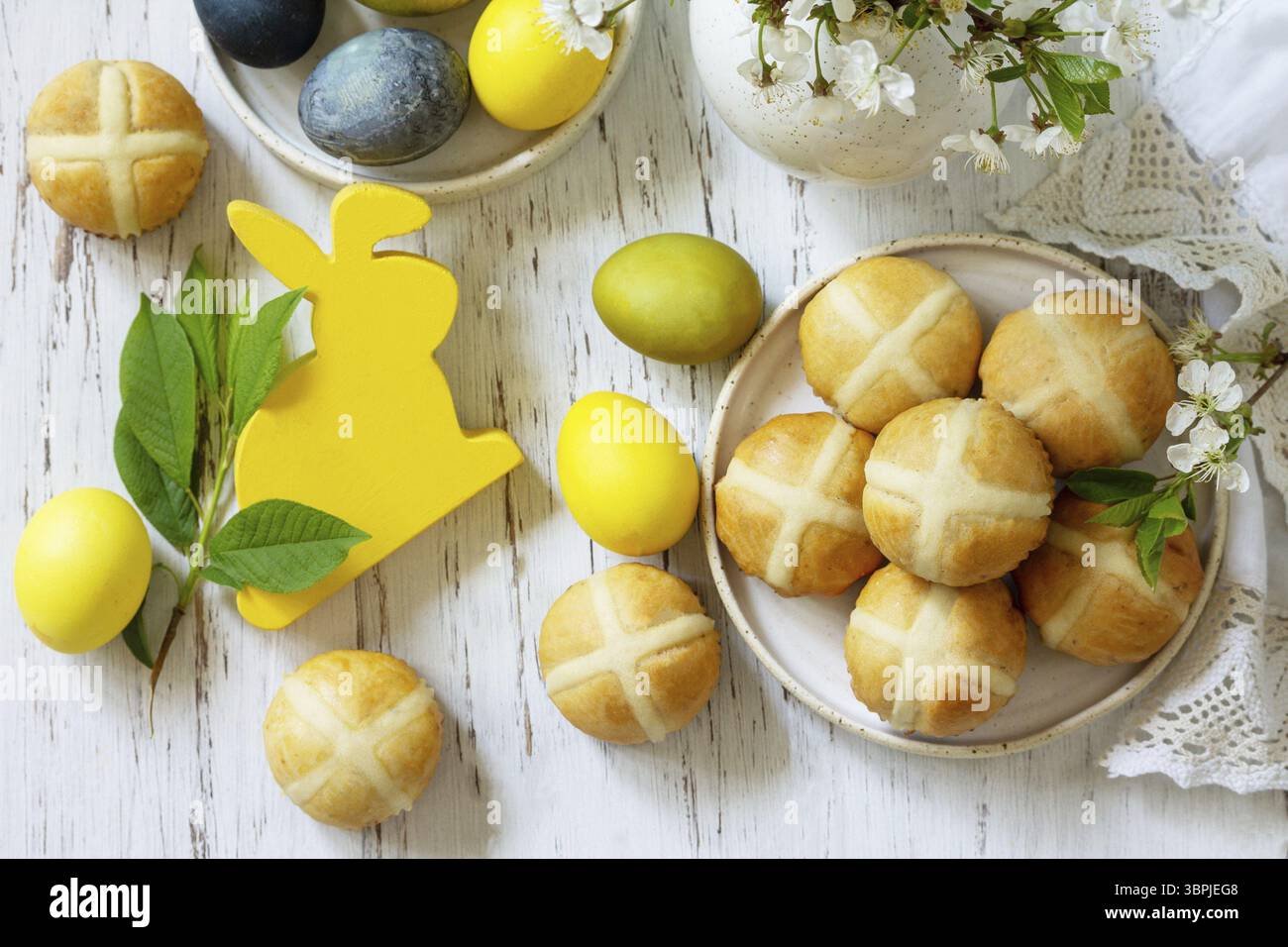Felice Pasqua cibo festivo concetto. Tradizionale croci pasquali caldi fatti in casa con uva passa e uova pasquali colorate naturali su un tavolo rustico. Vista dall'alto Foto Stock Felice Pasqua cibo festivo concetto. Tradizionale croci pasquali caldi fatti in casa con uva passa e uova pasquali colorate naturali su un tavolo rustico. Vista dall'alto Foto Stock